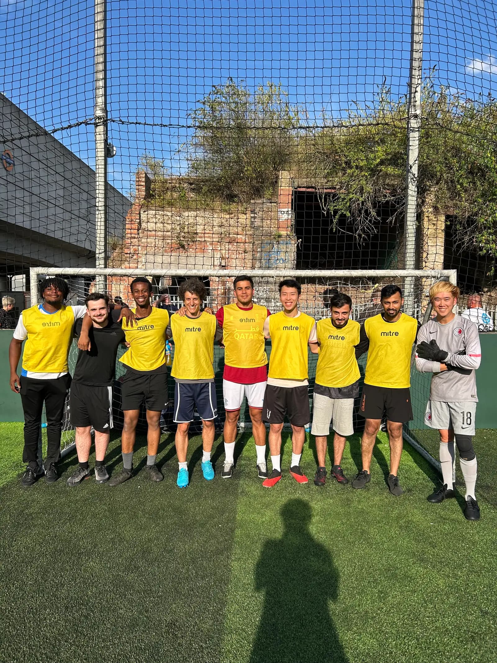 An Adobe tournament team in yellow bibs posing together in the goalmouth before their match.
