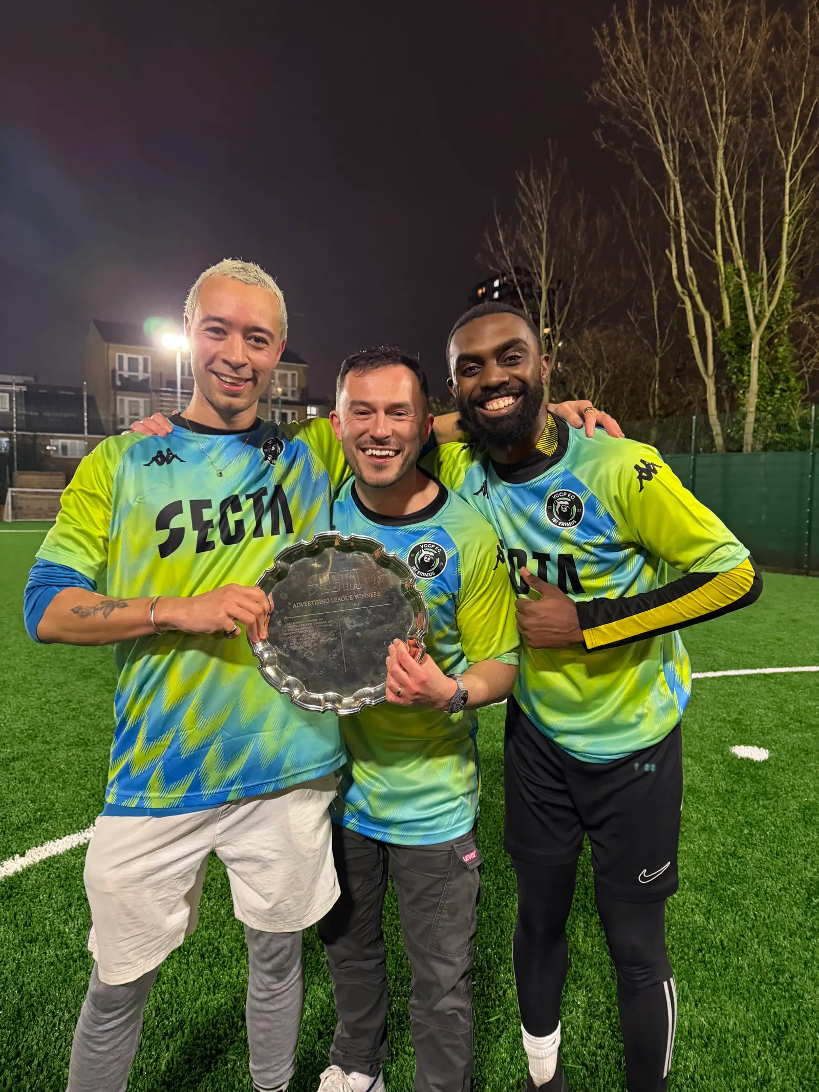 A winning team lifting the trophy in Secta-branded kit at the end of a corporate tournament.